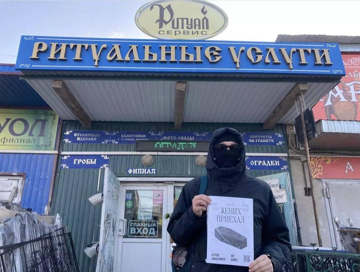 Айхал Аммосов с плакатом «Жених приехал» около ритуального агентства